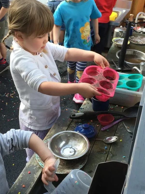Child pouring water at the outdoor mud kitchen, Ysgol Feithrin Y Trallwng, Welshpool