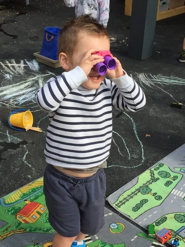 Child bug hunting with binoculars in the nursery garden, Ysgol Feithrin Y Trallwng, Welshpool